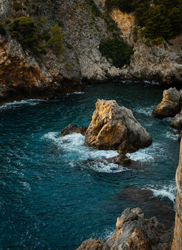 Deep blue Adriatic Sea crashing against rugged limestone cliffs and coastal rocks in Dalmatia.
