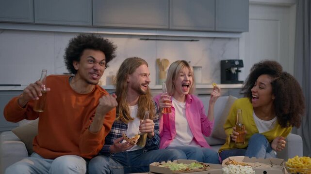 Excited cheerful multiracial friends watching sport match on couch home cheering celebrating win joyful African Caucasian women men together weekend holiday group yelling rejoice team TV game indoor