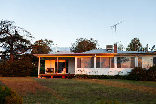 sunset light reflecting in windows of farmhouse in Australian countryside