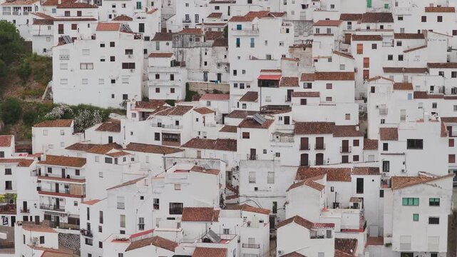 Aerial view of the traditional white houses and terracotta rooftops of a hillside village in Casares, Andalusia, Spain.