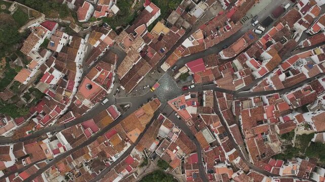 Aerial view of the terracotta rooftops and narrow winding streets of the historic white village Casares, Andalusia, Spain.