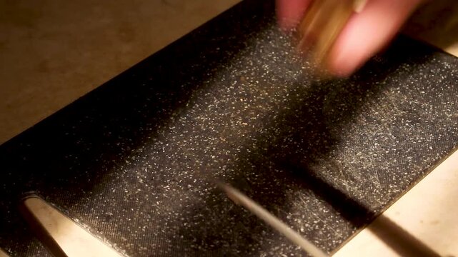 Chef hands slicing fresh mushrooms on black cutting board with sharp knife in kitchen