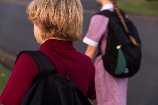 close up of a child in uniform with a backpack with another child in background