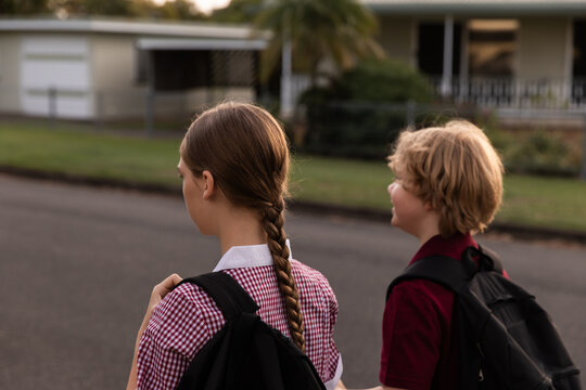 boy and girl in school uniform walking along an empty street