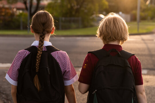 children in school uniform walking on a quiet street from the back