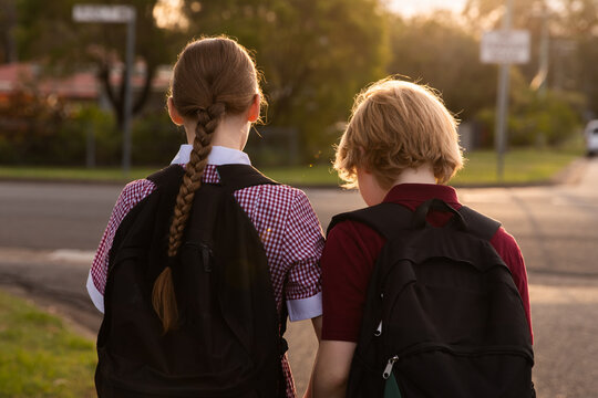 brother and sister walking in school uniform with backpacks