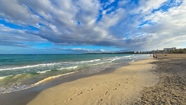 Wide angle view of Cala Millor beach in Mallorca with footprints in the sand and dramatic clouds