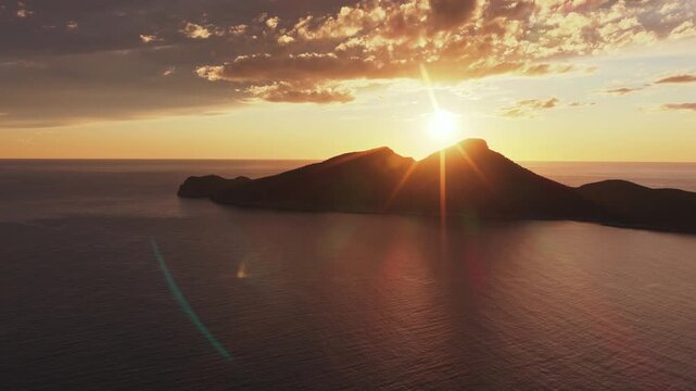 Aerial view of Sa Dragonera island at sunset with golden light reflecting on the Mediterranean sea and clouds Sant Elm, Balearic Islands, Spain.