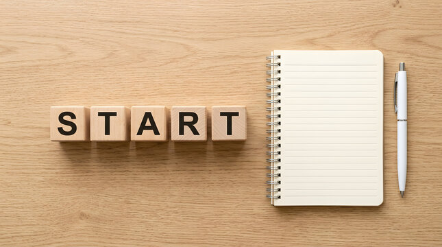 START Blocks and Notebook: The word START spelled out with wooden letter blocks, placed next to a blank spiral notebook and a pen on a wooden surface, symbolizing new beginnings and planning.