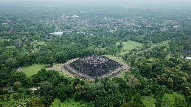 Aerial view of Borobudur Temple in Indonesia surrounded by lush green trees.