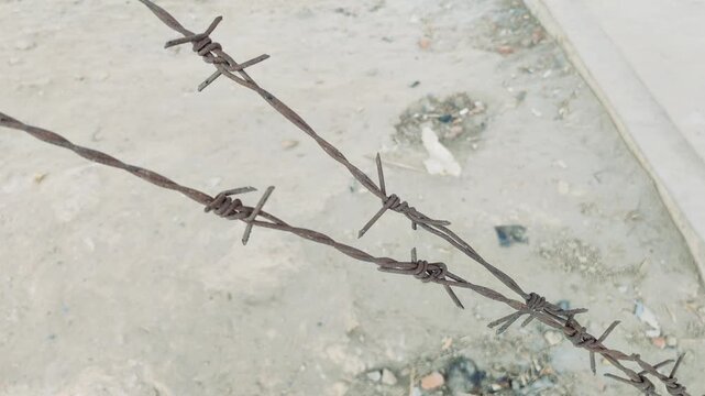 Rusty Barbed Wire Fence on Sandy Ground Used for Boundary Protection in Rural Bangladesh Environment