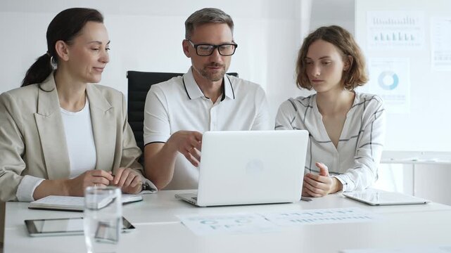 Professional team analyzing data on laptop, sharing insights during collaborative office meeting, highlighting workplace synergy and strategic planning