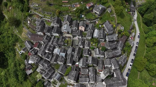 Aerial view of Corippo Albergo Diffuso featuring traditional stone houses with slate roofs nestled in the lush green hills of Ticino, Corippo, Ticino, Switzerland.