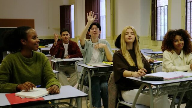 Happy multinational students listening to a lesson and raising hands in a high school classroom