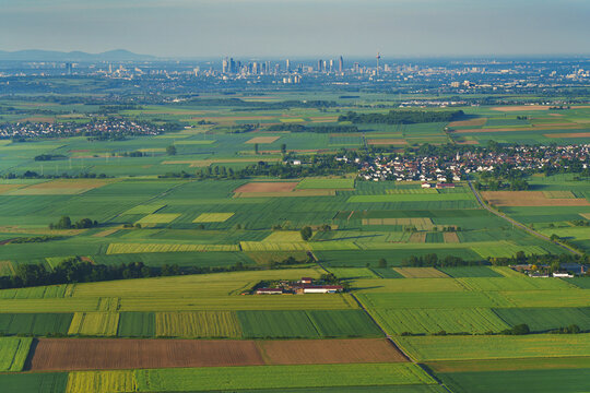 Aerial view of a field at sunrise. A landscape from a drone perspective, with a view of the metropolis of Frankfurt am Main. An agricultural landscape from the air.