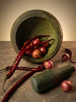 Traditional Stone Mortar and Pestle with Red Chili and Shallot on Rustic Table
