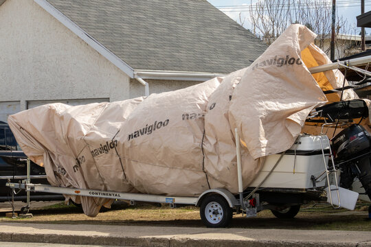 La Tuque, Canada, 10 May 2026 : A boat covered with a "navigloo" tarp sits on a "CONTINENTAL" trailer with a "SUZUKI" outboard motor.