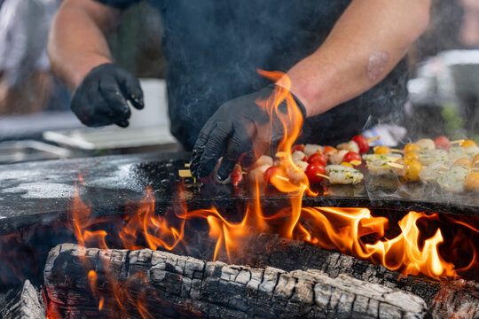 Pr&eacute;paration de brochettes de fruits de mer sur brasero avec cuisson au feu de bois et fum&eacute;e en ext&eacute;rieur.