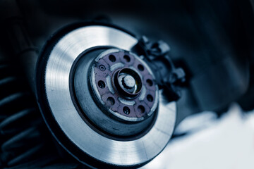 Closeup of steel brake disc in car service replacing wheel pads in garage.