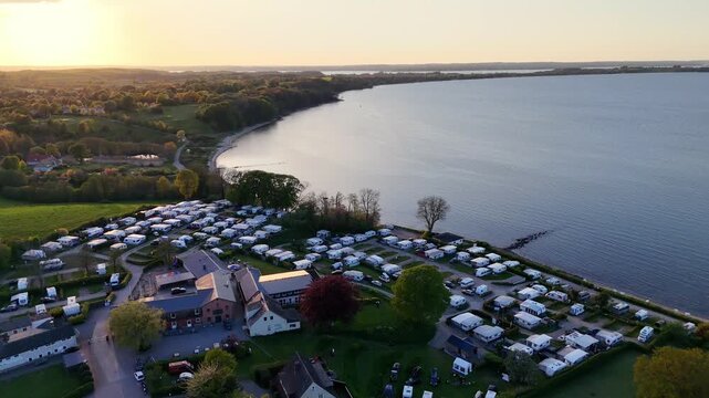 Aerial view of Bockholmwik campsite with rows of caravans along the coast during golden hour in Munkbrarup, Schleswig-Holstein, Germany.