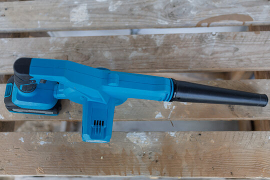 High angle top view of a blue battery operated leaf blower placed on a rustic wooden pallet structure