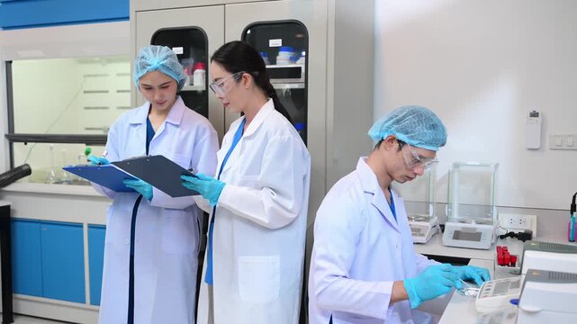 Young scientists conducting research investigations in a medical laboratory, a researcher in the foreground is using a microscope in laboratory for medicine.