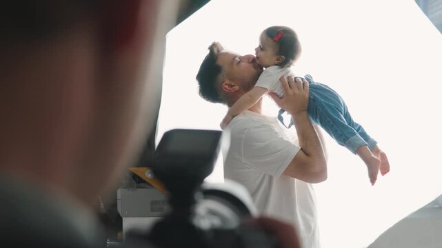  Father taking daughter in his arms in photo studio.