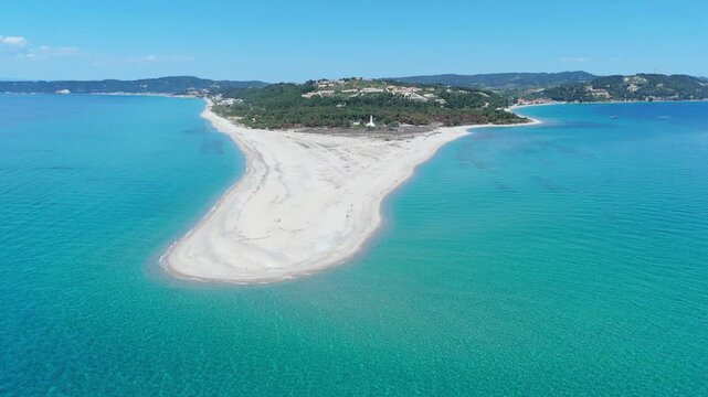 Aerial view of Possidi Beach sandy cape stretching into the turquoise Aegean Sea with lush green hills in the background under a clear blue sky Greece.