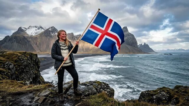 Woman displaying Iceland flag, celebrating national independence day, situated rugged coastal cliff, powerful ocean surf, snow capped mountain, dark volcanic sand, overcast sky.