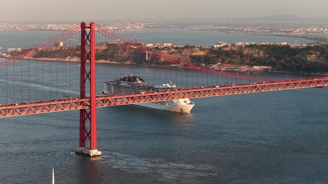 Aerial view of 25 de Abril Bridge in Lisbon with cruise ship on Tejo River at sunset.
4K high quality cinematic city footage.