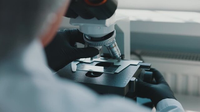 Laboratory technician changing microscope objective lenses during analysis
