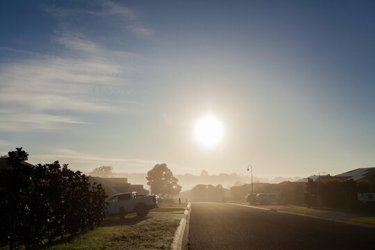 Urban street scene with morning light through mist hiding houses along road
