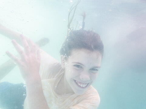 Australian tween girl swimming underwater in backyard pool enjoying cool water