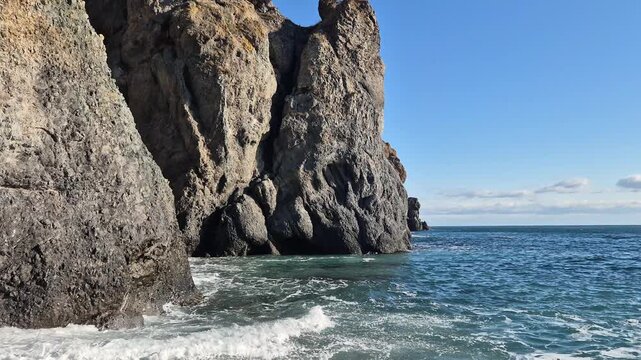 Coast rock ocean waves crashing against majestic sea cliffs under a bright sun in a serene natural environment
