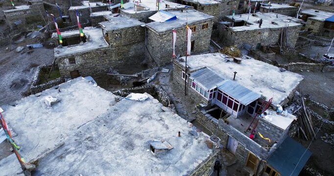 An aerial view of a traditional Himalayan stone village with flat rooftops and prayer flags in Nepal.
