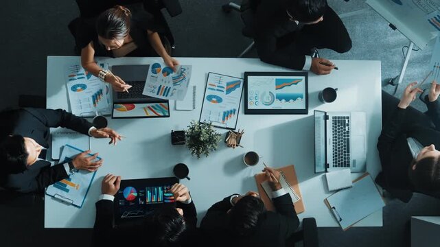 Time lapse of business team analyze financial graph and plan marketing strategy while pointing mind map at whiteboard. Top down aerial view of diverse people brainstorm creative idea. Directorate.