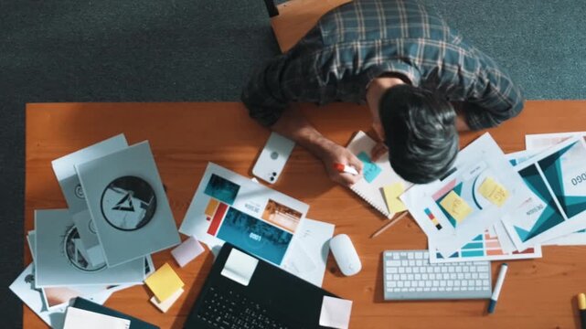 Aerial view of smart businessman calling manager while choose color. Professional interior designer looking at laptop screen while select and design main theme color for product at meeting. Symposium.