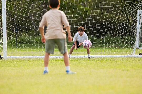 Young soccer player on defensive stance in front of soccer goal net during penalty kick