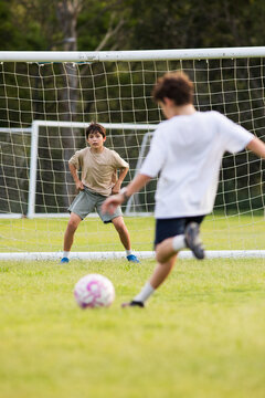 Young soccer player on defensive stance in front of soccer goal net during penalty kick
