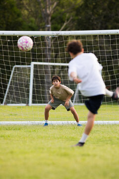 Young soccer player on defensive stance in front of soccer goal net during penalty kick