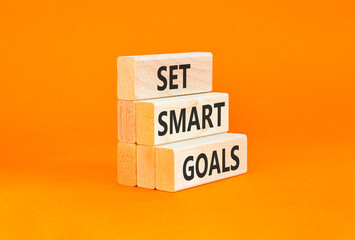 Naklejka premium Set smart goals words symbol. Concept words Set smart goals on beautiful wooden blocks. Beautiful orange background. Business and set smart goals concept. Copy space.