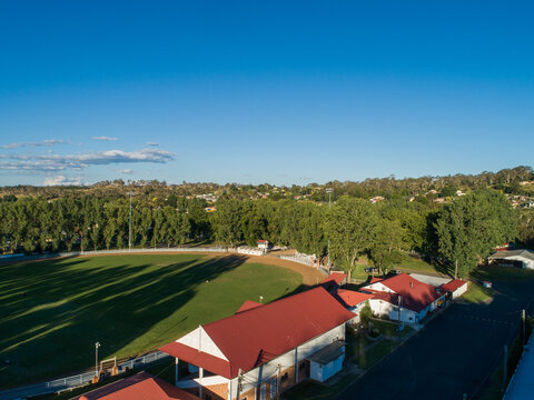 Red roofed building around Glen Innes Showground ring in bright sunlight from aerial