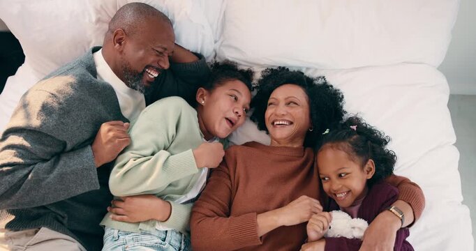 Face, family and children relax on bed above with bonding, cuddle and happiness in home. Smile, playful and mother with father laughing and hug daughter for weekend fun, connection and comfort