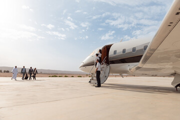 Business executives boarding a private jet for luxury travel at a desert airport © .shock