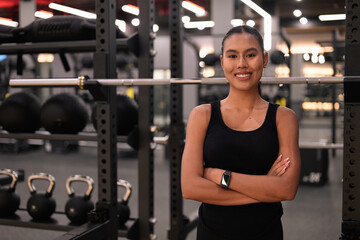 Fototapeta premium Asian Thai Isan Woman Smiling with Crossed Arms at Gym at Night