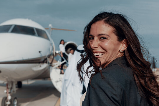 Confident businesswoman smiling while boarding a private jet for luxury business travel
