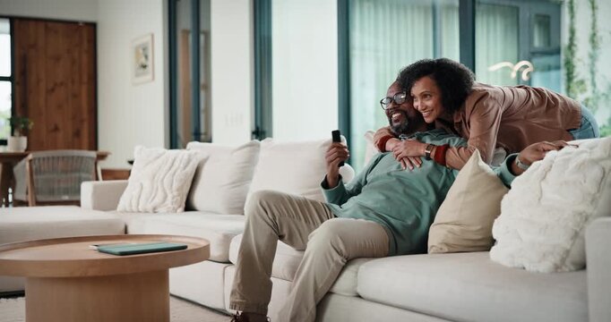 Couple, watching tv and hug on sofa with smile, bonding and surprise with love in living room. Mature man, woman and embrace with movies, television or film subscription on couch in lounge at house