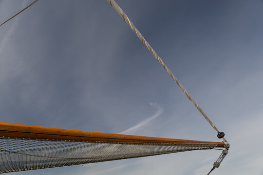 Bowsprit and furled headsail against blue sky on a classic sailing vessel, geometric composition