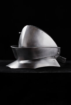 Shiny articulated steel gorget displayed on a dark backdrop, highlighting curved metal plates and riveted construction of traditional medieval neck armor.