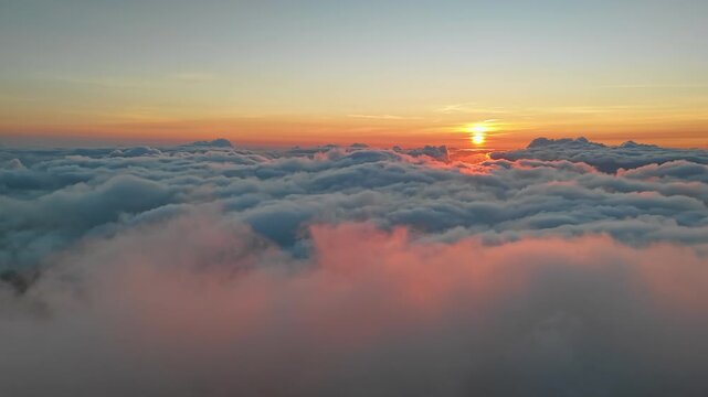 Timelapse of sunrise above moving clouds at Pico do Arieiro, Madeira Island. Aerial drone view showing flowing cloud layers and warm morning light over the mountain landscape